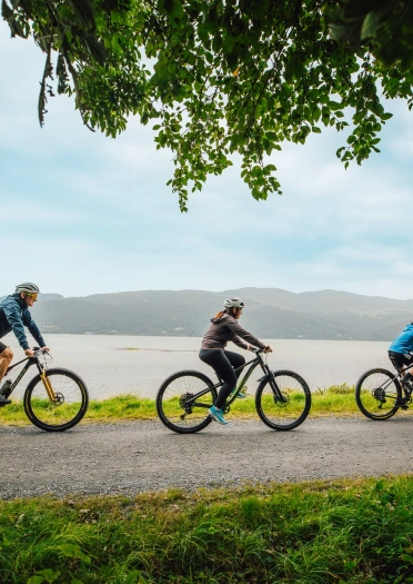 family of three on bikes on trail.