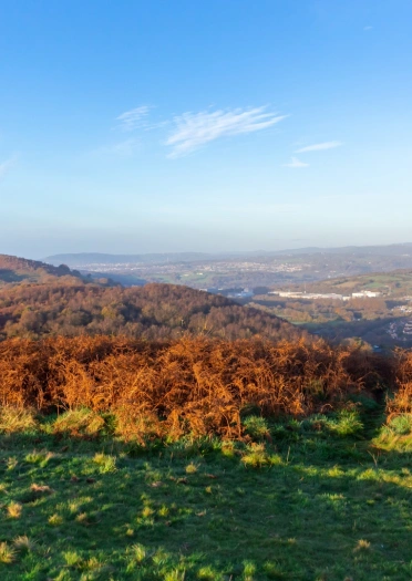 views from the top of a mountain, overlooking a town surrounded by green hills.