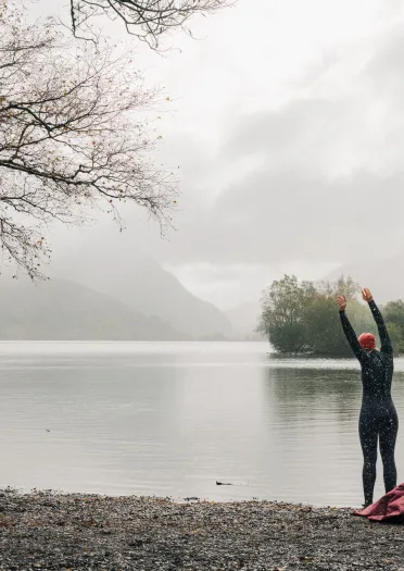 Tri ffrind yn nofio mewn dŵr oer yn Llyn Padarn, Parc Cenedlaethol Eryri (Eryri), Gogledd Cymru