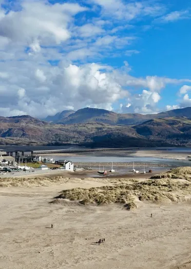 sandy beach with mountains in the distance on a sunny day.
