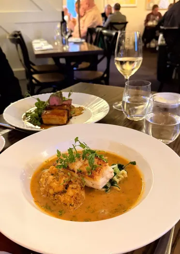 Plates of food and glasses on wine on table.