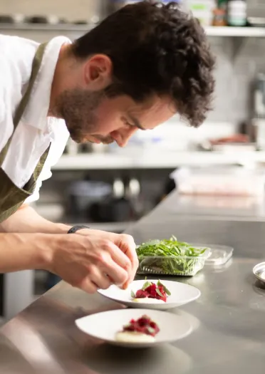 A chef putting final touches to a plate of food.