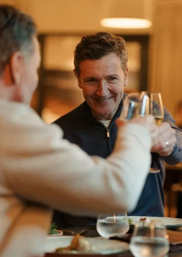 A smiling couple clinking glasses of champagne at a candlelit table,  in a romantic setting