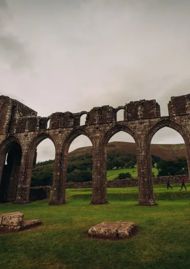 A ruined priory building with dramatic stone arches.