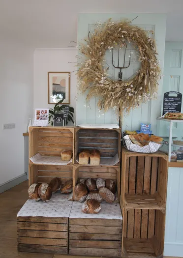 display in show with pitchfork, gold wreath and bread in wooden crates.