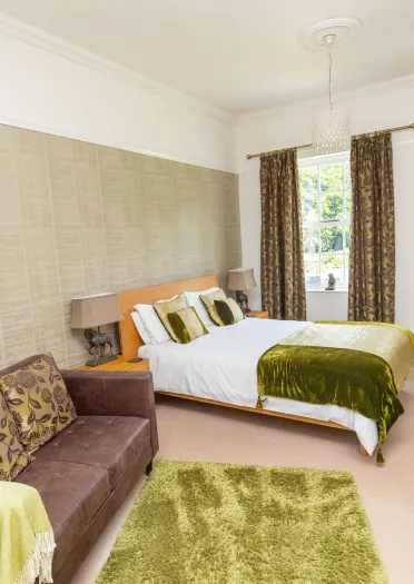 luxury hotel room with sofa, rug, bed, chair and desk.