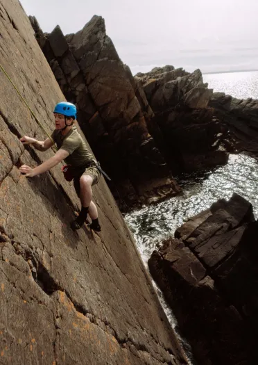 climbing wearing helmet climbing sea cliff.