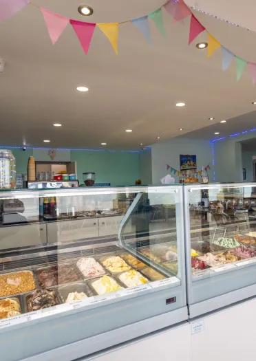 Interior of Zio’s Gelateria with glass display counters filled with gelato and colourful bunting hanging from the ceiling.