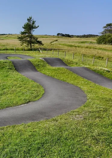 A tarmac cycling pump track with bumps and tight corners.