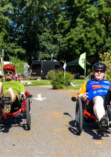 Two cyclists on a pathway in a park.