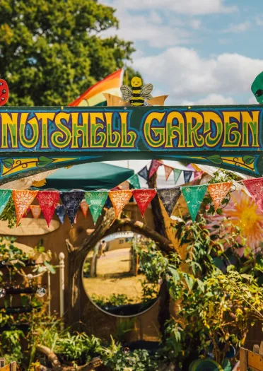 Hand-painted 'Nutshell Garden' sign over a small garden.