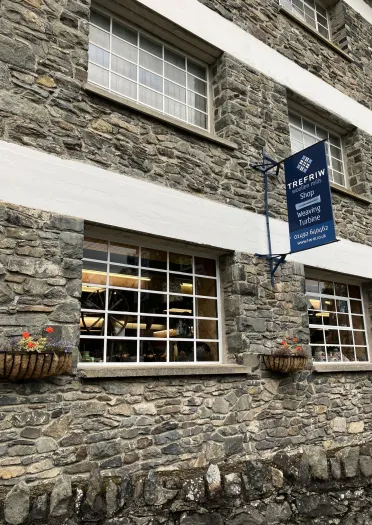 Exterior of a stone built woollen mill building, with large windows.
