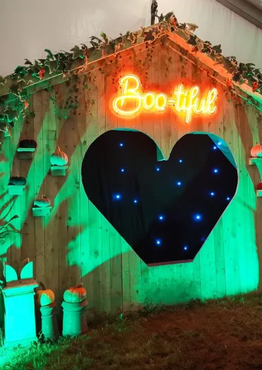 Halloween display with a glowing ‘Boo-tiful’ sign, pumpkins and green lighting.