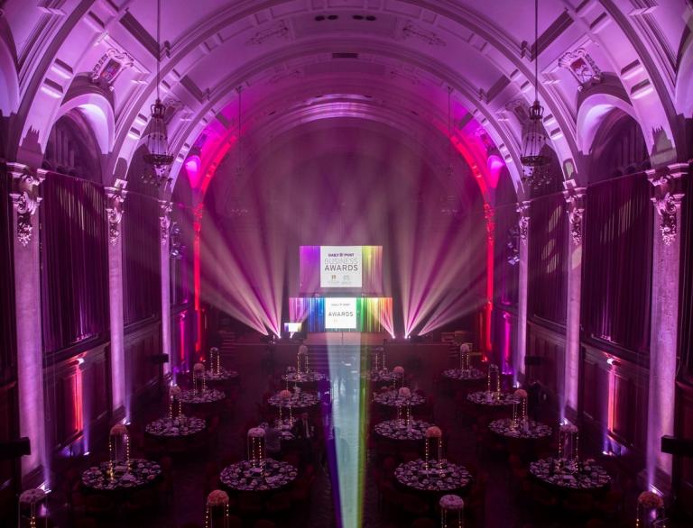 A university hall lit up and laid out for a gala dinners for an awards evening.