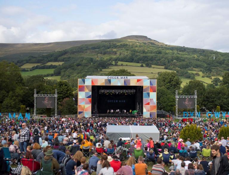 A crowd of festival goers looking at the main stage with mountains in the background at Green Man Fesitval.