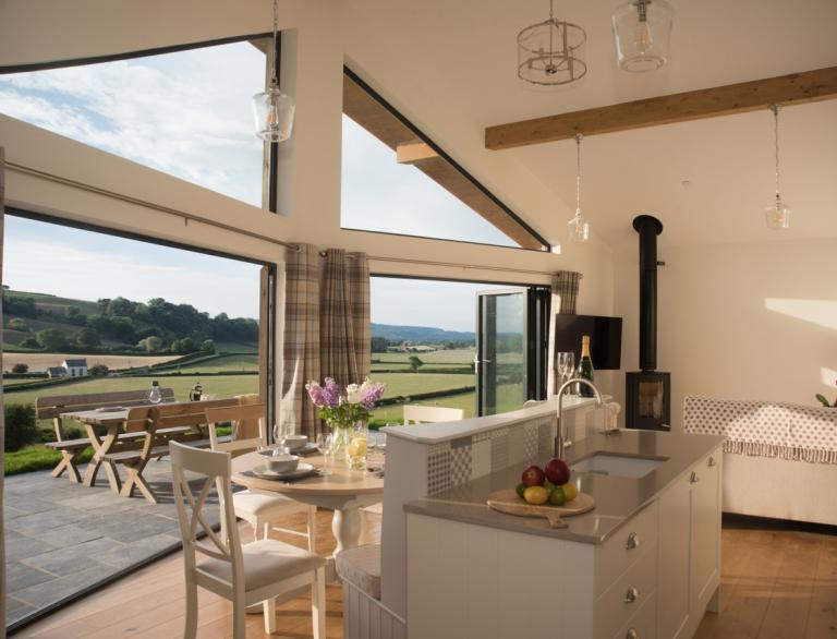 Sleek interior of architect designed cottage with views through bi-fold doors. 