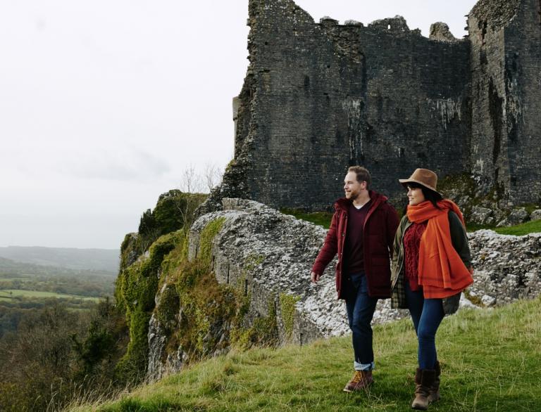 Ein Paar, das im Herbst in der Nähe der Ruinen einer Burg spazieren geht.
