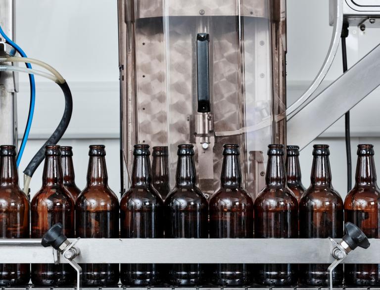 Reihen von Flaschen auf einem Fließband in einer Brauerei.
