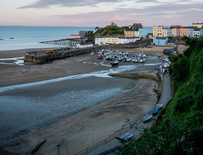 Tenby harbour at low tide with houses and Caldey Island in the background.