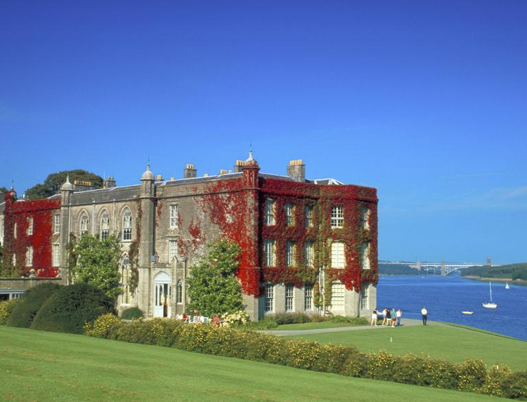 Exterior view of Plas Newydd covered in red creeping ivy with the sea in the background.