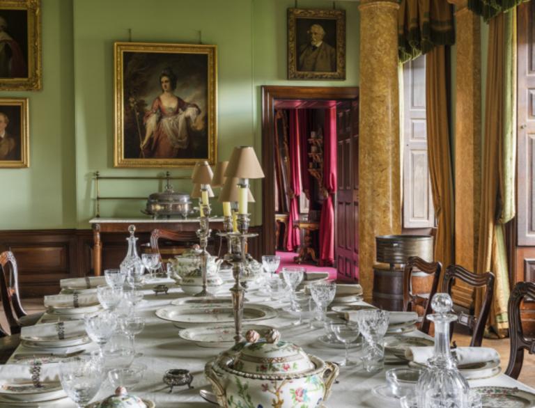 A table set for grand dining with portraits on the wall and a pillar in the background at Erddig House.