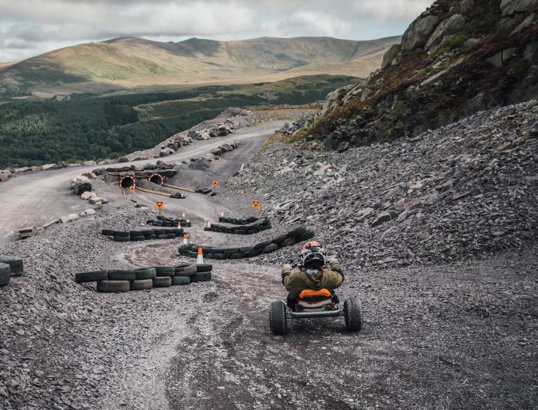A go cart travelling down a slalom obstacle course of tyres and tunnels at a former slate quarry.