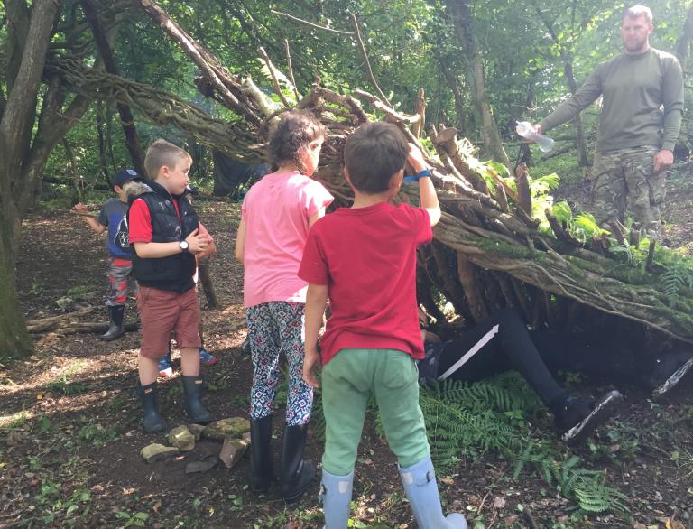 Young children building a shelter from wood.