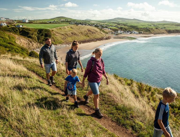Tow adults and two children walking along a cliff edge.