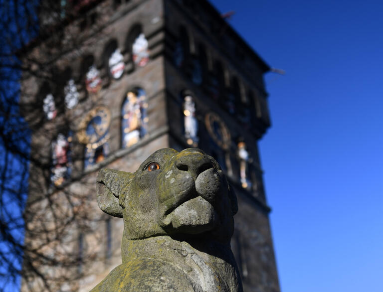 Cardiff Castle clock tower with a stone animal in front.