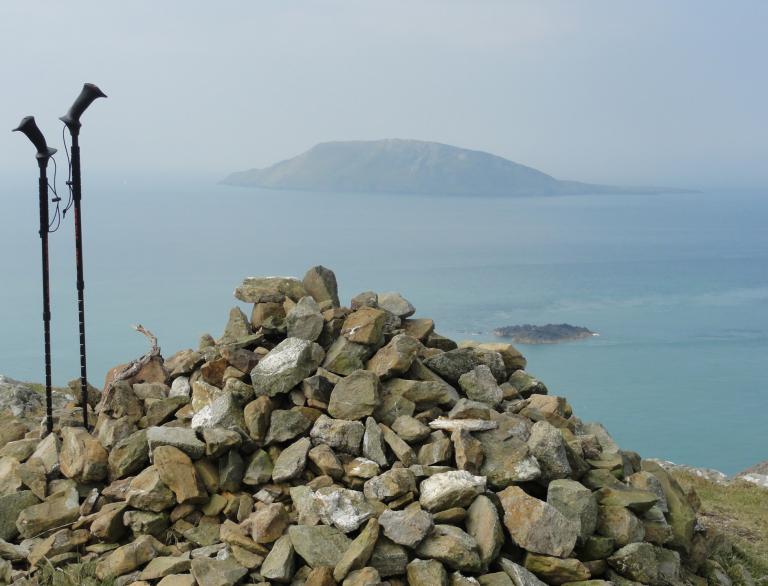 View of Bardsay Island from a pile of stones with two walker's poles next to them.