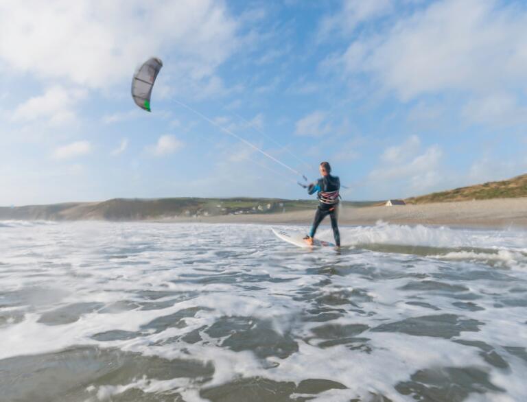 A man kitesurfing at Newgale beach with sand in distance