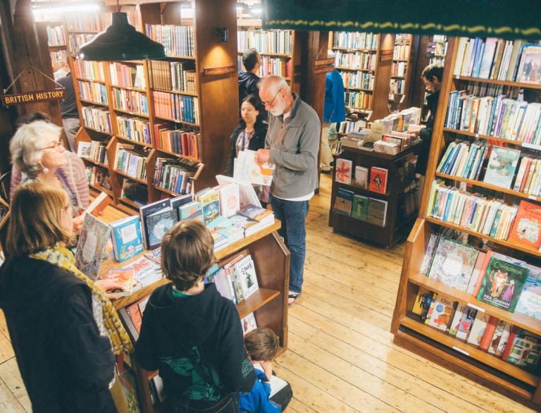 People in a bookshop, amongst shelves full of books.