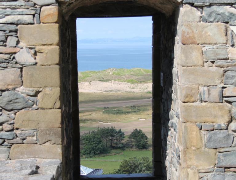 Views through a castle doorway towards a beach.