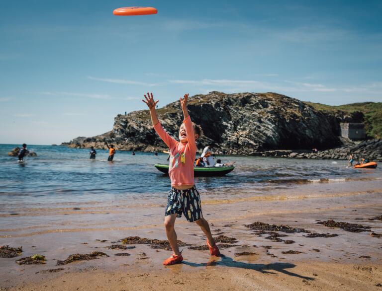 A young child playing with a frisbee on a beach.