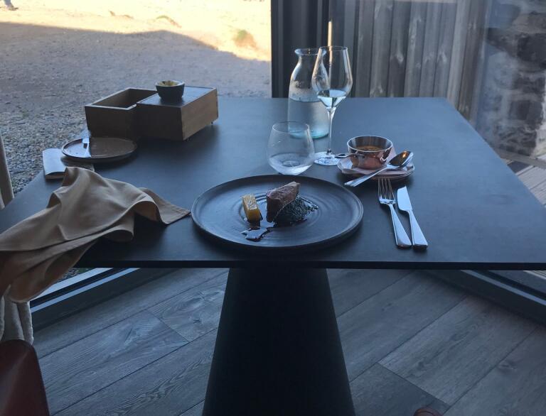 A restaurant table by a window looking out onto a beach.