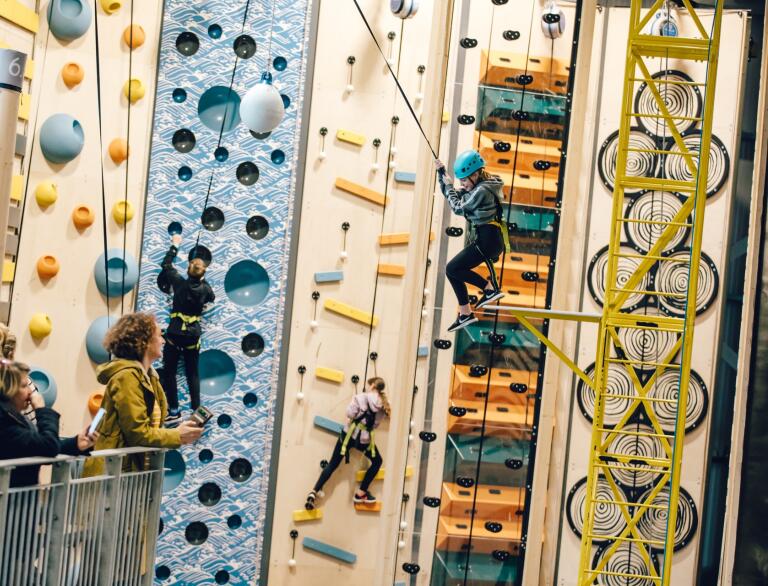 People climbing up an indoor climbing wall.
