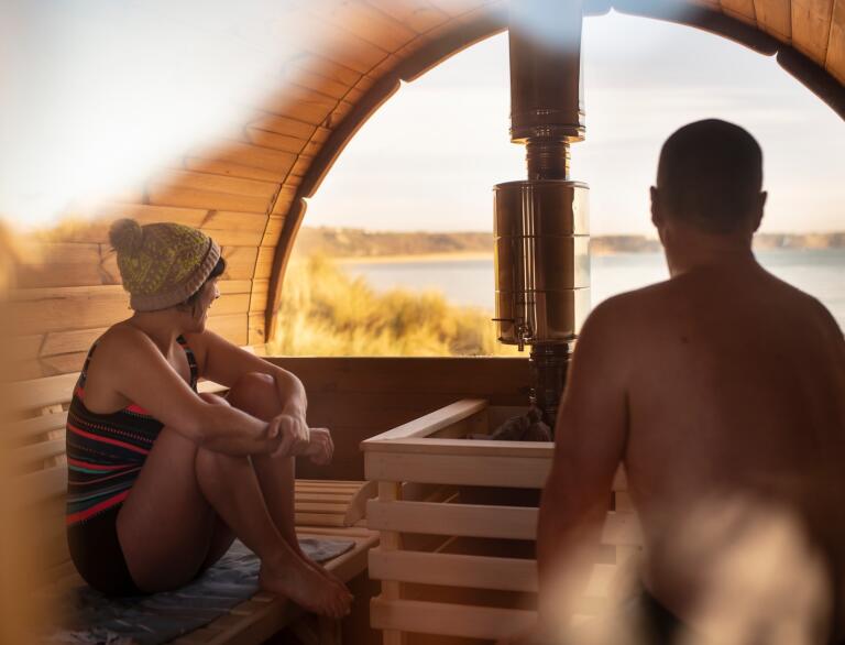 man and woman in sauna looking out to beach.