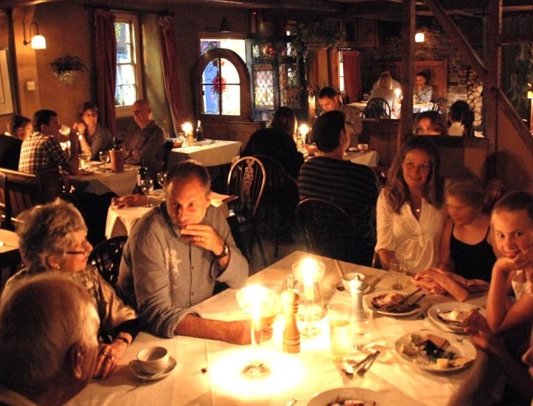 groups of people eating at tables by candlelight.