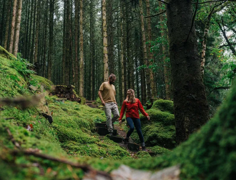 man and woman walking down steps in wood.