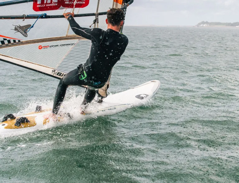 A man on a windsurfing board out on the water.