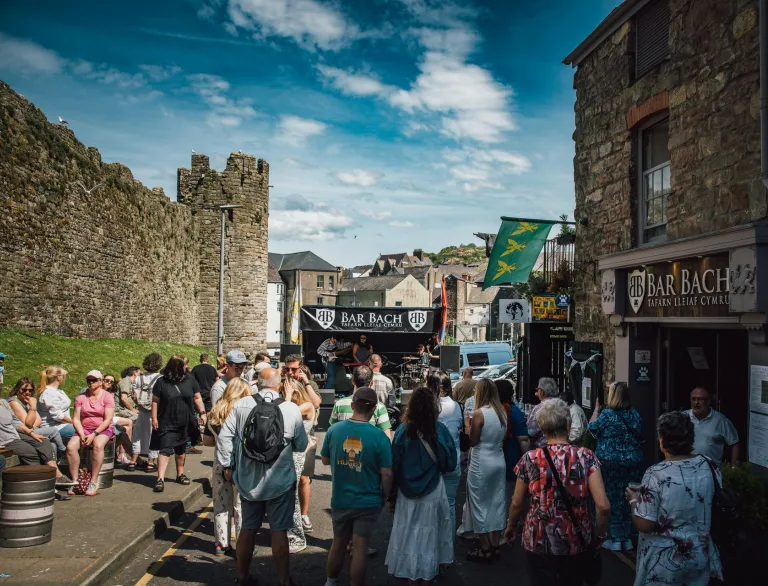 Busy food stalls at a festival, underneath a castle.