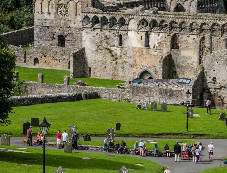 Ruins of the Bishops' Palace with people on the green in front.