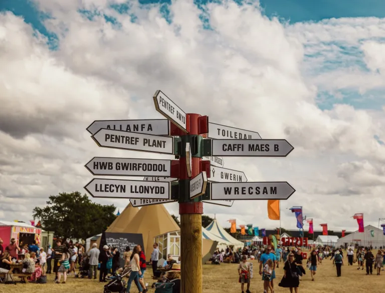 sign in Welsh language at Eisteddfod with people and tents.