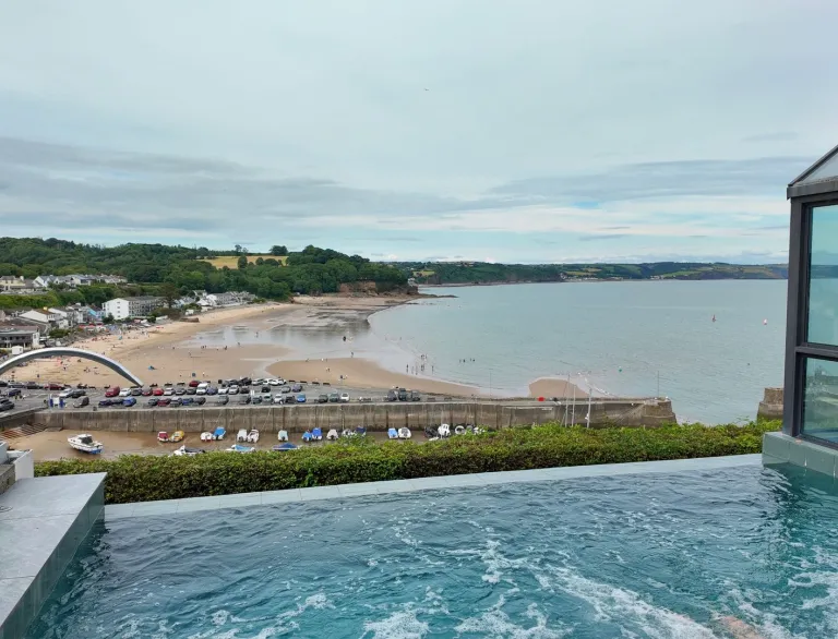 An infinity pool overlooking a pretty beach and village.