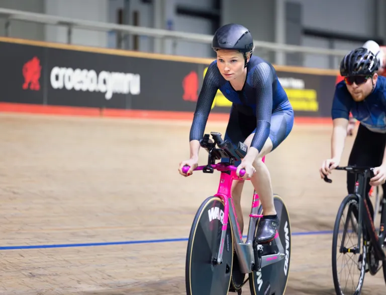 cyclists cycling in velodrome.