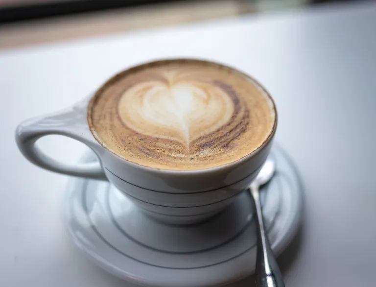 A white cup and saucer with a latte