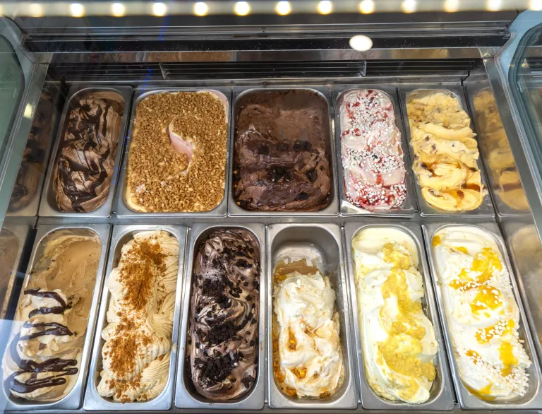 Selection of gelato flavours displayed in metal trays inside a refrigerated counter at Zio’s Gelateria