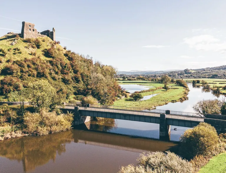 Ruined hilltop castle overlooking a bridge and the River Tywi valley.