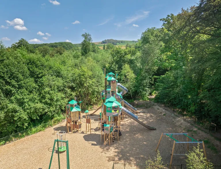 Adventure playground at Gnoll Country Park featuring climbing towers, slides and swings surrounded by woodland.