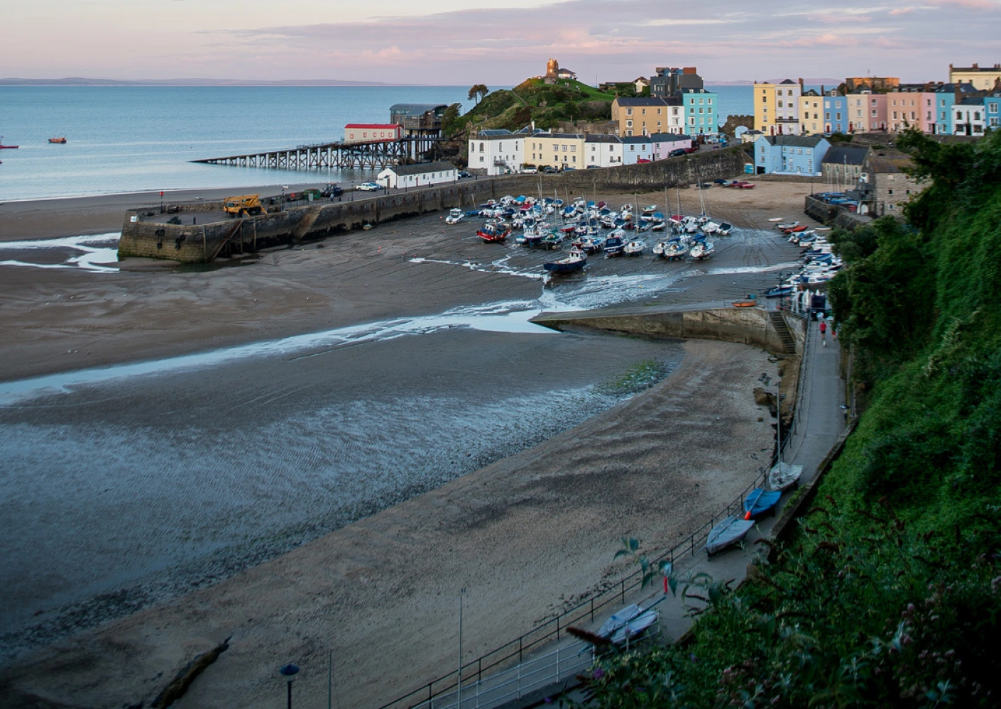Tenby harbour at low tide with houses and Caldey Island in the background.